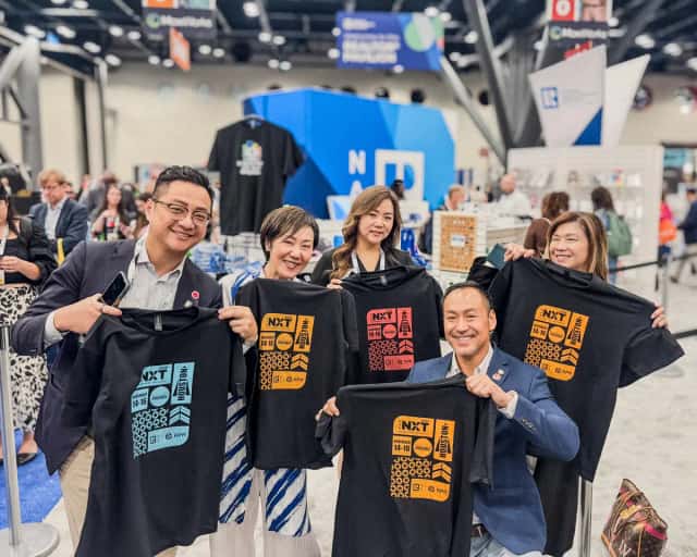 Guests on a convention floor holding freshly printed event tees