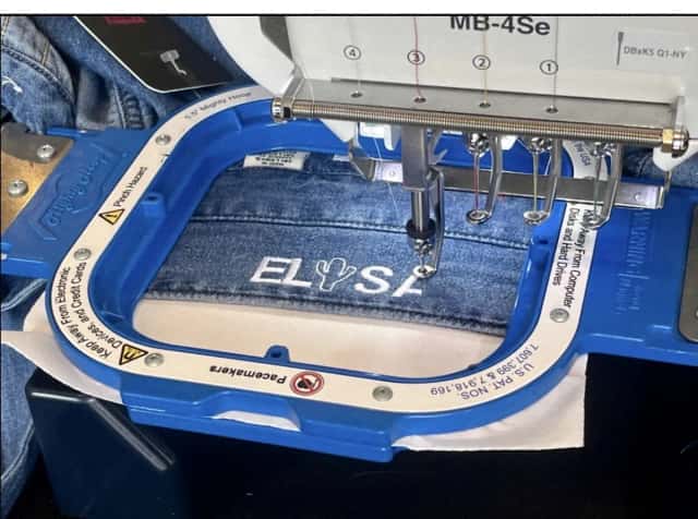 A name being embroidered onto denim on site